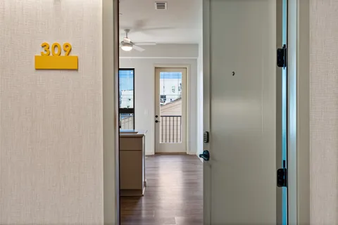 a view of a hallway with wooden floor and a bathroom