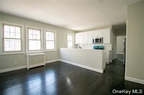 a view of a kitchen with wooden floor and electronic appliances