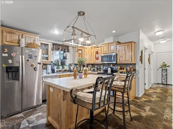 a kitchen with stainless steel appliances kitchen island granite countertop a refrigerator a oven a sink a dining table and chairs