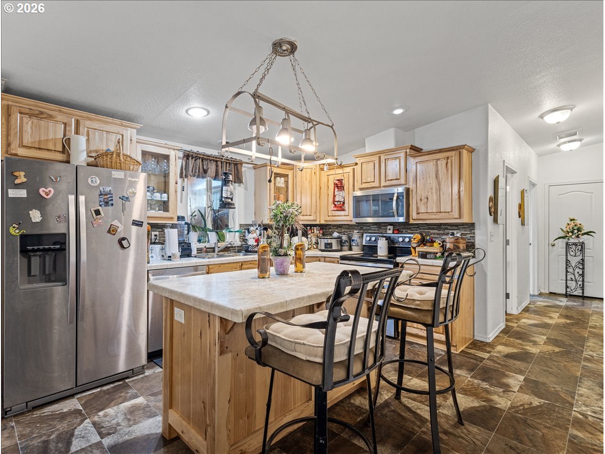 23728 Northeast Dole Valley Road Yacolt, WA 98675 - Photo 15 of 46 a kitchen with stainless steel appliances kitchen island granite countertop a refrigerator a oven a sink a dining table and chairs