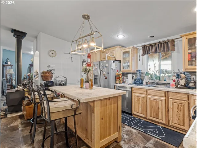 a kitchen with stainless steel appliances kitchen island granite countertop a table chairs sink and cabinets