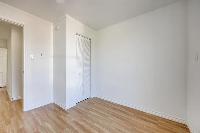 a view of an empty room with wooden floor and closet
