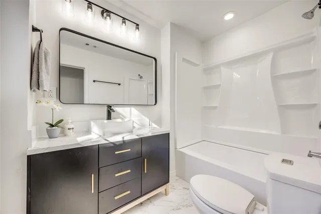 a bathroom with a granite countertop sink toilet a large mirror a vanity and shower