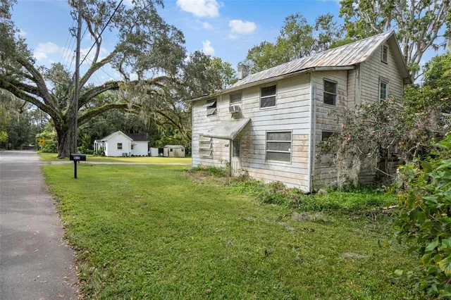 a view of a house with backyard and trees