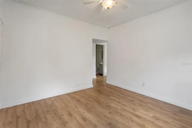 an empty room with wooden floor chandelier fan and closet area