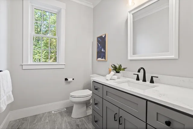 a bathroom with a granite countertop toilet sink and mirror