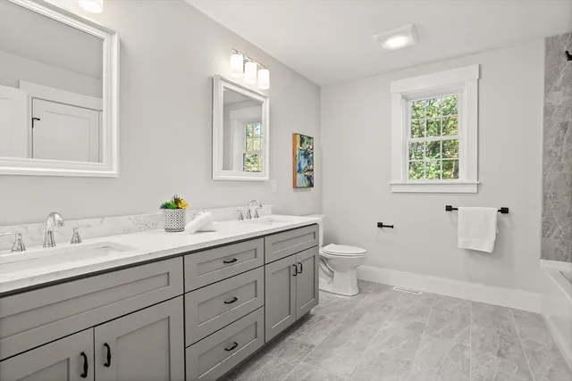 a bathroom with a granite countertop toilet sink and mirror