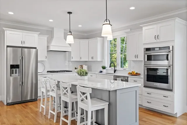 a kitchen with stainless steel appliances granite countertop a stove a refrigerator and a kitchen island with wooden floor