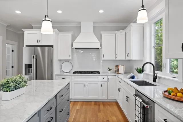 a kitchen with stainless steel appliances a sink a stove a refrigerator cabinets and wooden floor