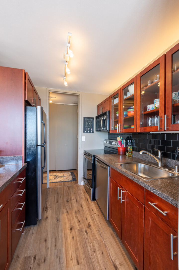 655 West Irving Park Road, Unit 4616 Chicago, IL 60613 - Photo 13 of 25 a kitchen with stainless steel appliances granite countertop a sink dishwasher stove and refrigerator with wooden floor