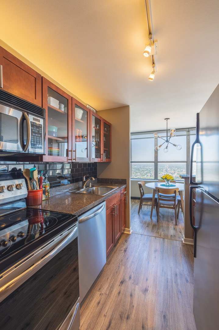 655 West Irving Park Road, Unit 4616 Chicago, IL 60613 - Photo 14 of 25 a kitchen with stainless steel appliances granite countertop a sink dishwasher stove and cabinets with wooden floor