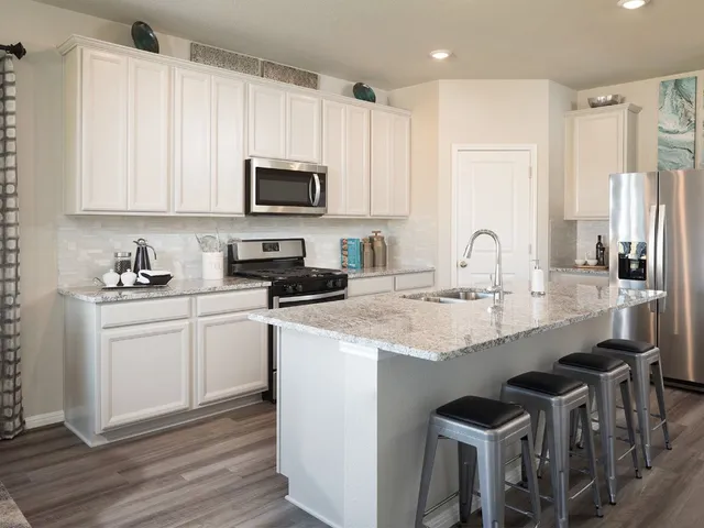 a kitchen with stainless steel appliances granite countertop a sink a stove a refrigerator and cabinets