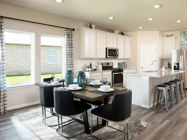 a kitchen with a dining table chairs and white appliances