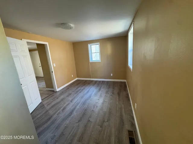 an empty room with wooden floor and window