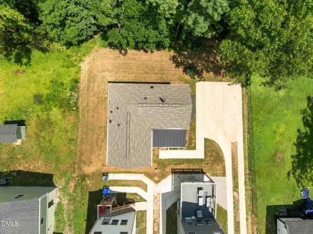 an aerial view of a house with outdoor space and trees all around