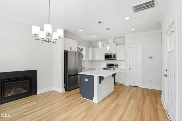 a large kitchen with stainless steel appliances granite countertop a stove a refrigerator and a fireplace with wooden floor