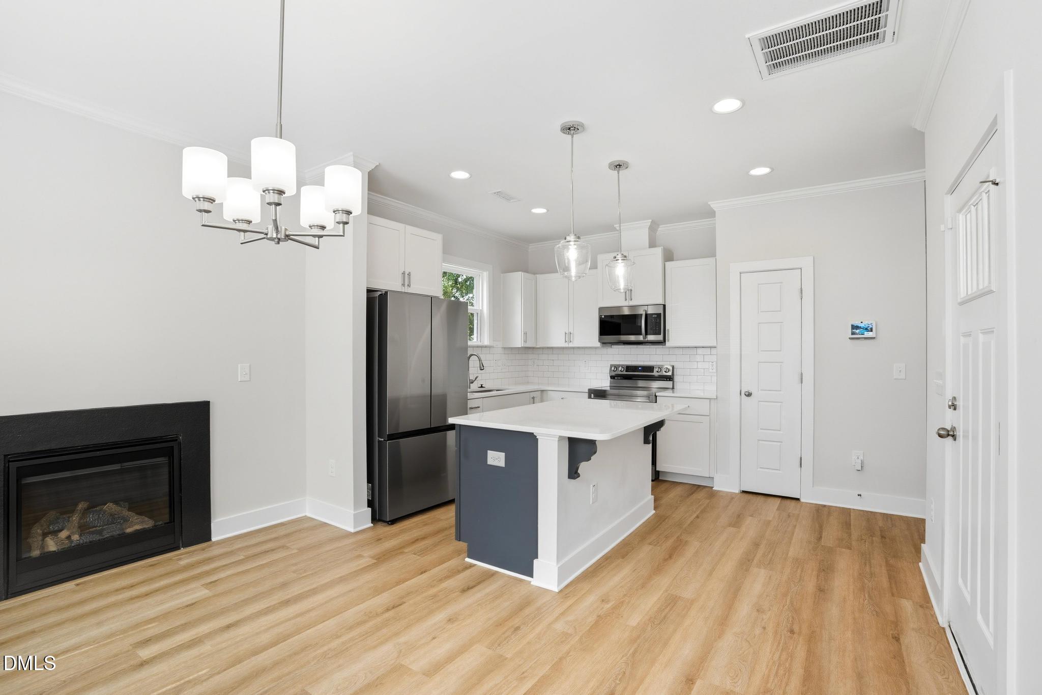 551 Homeland Avenue Durham, NC 27707 - Photo 7 of 32 a large kitchen with stainless steel appliances granite countertop a stove a refrigerator and a fireplace with wooden floor