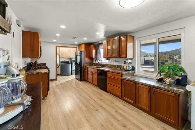 a large kitchen with stainless steel appliances granite countertop a stove a sink dishwasher and a refrigerator with wooden floor