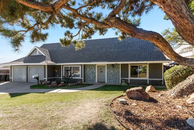 a view of a house with a yard covered with snow and a tree