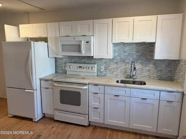 a kitchen with white cabinets white stainless steel appliances and sink