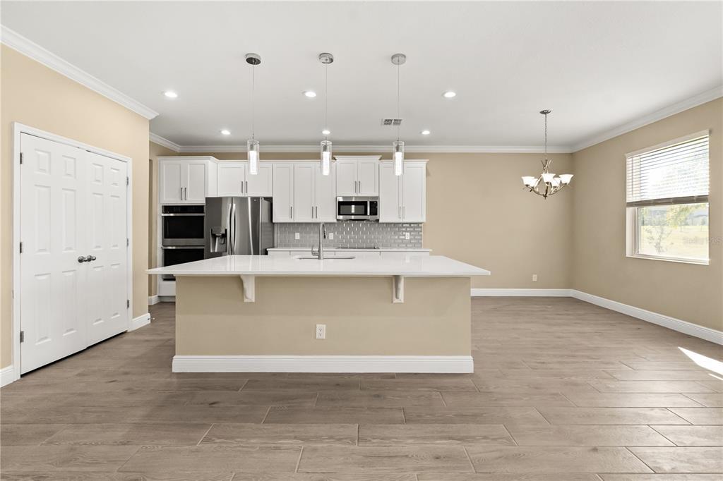 7757 Marsala Street Clermont, FL 34714 - Photo 15 of 75 a view of kitchen with stainless steel appliances granite countertop a stove a sink a refrigerator and white cabinets with wooden floor