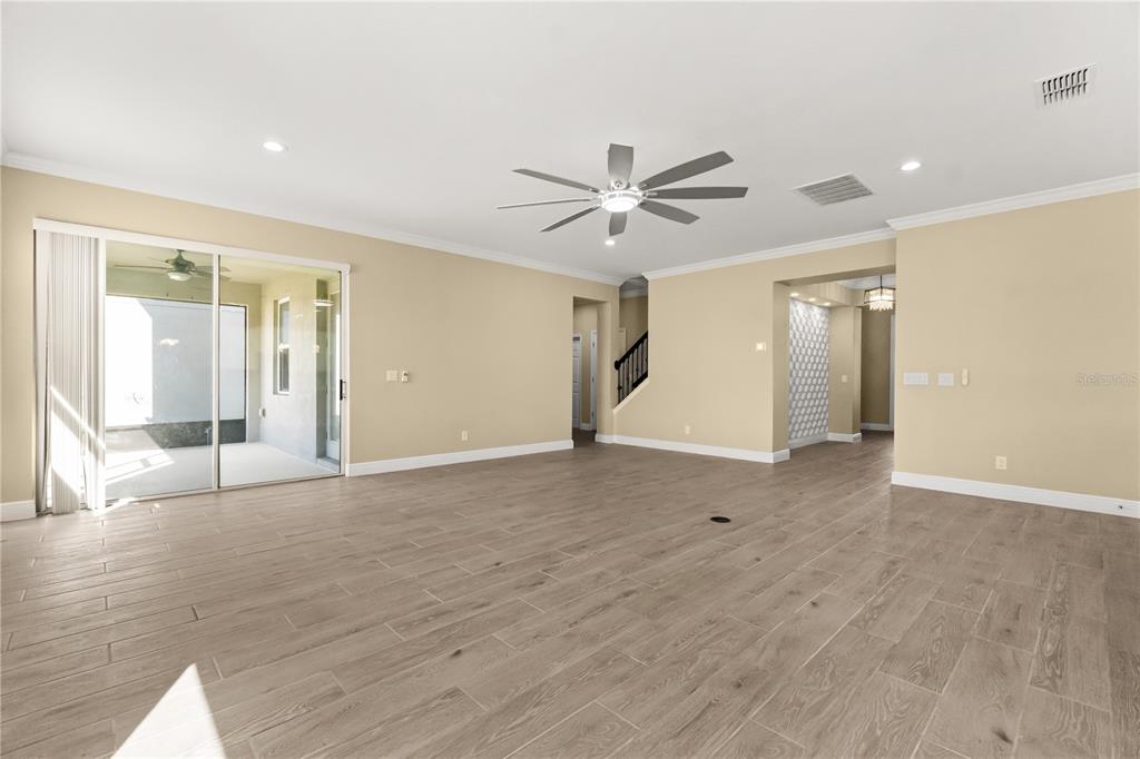 7757 Marsala Street Clermont, FL 34714 - Photo 16 of 75 a view of an empty room with wooden floor and a ceiling fan