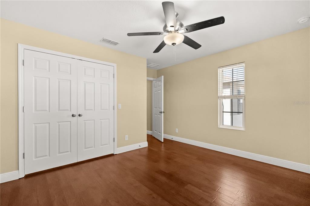 7757 Marsala Street Clermont, FL 34714 - Photo 23 of 75 an empty room with wooden floor chandelier fan and windows