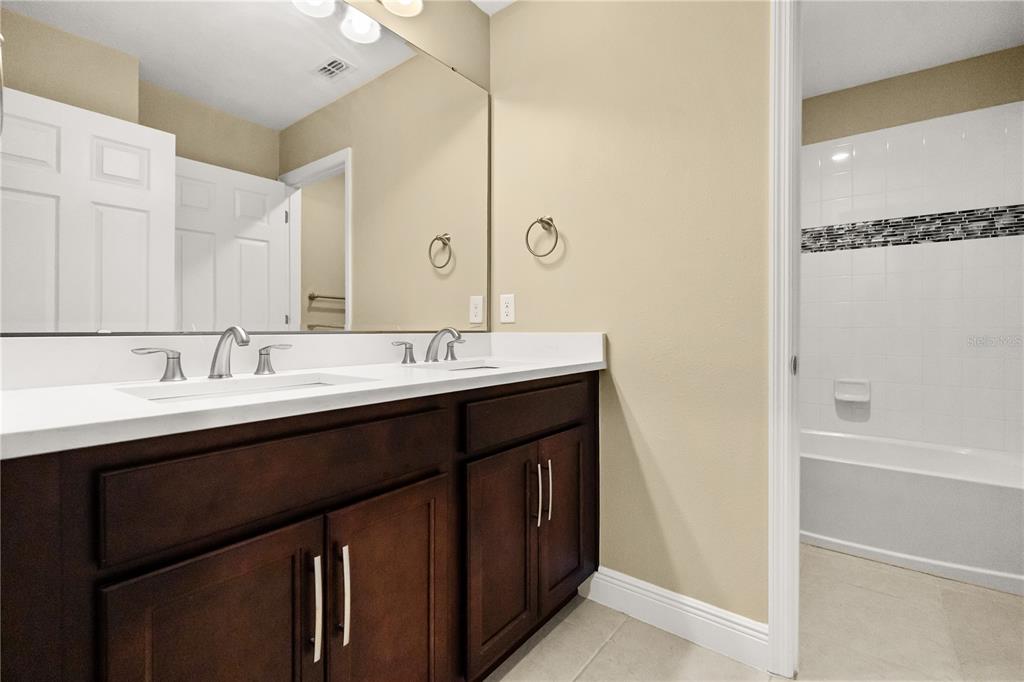 7757 Marsala Street Clermont, FL 34714 - Photo 24 of 75 a bathroom with a double vanity sink a mirror and a bathtub