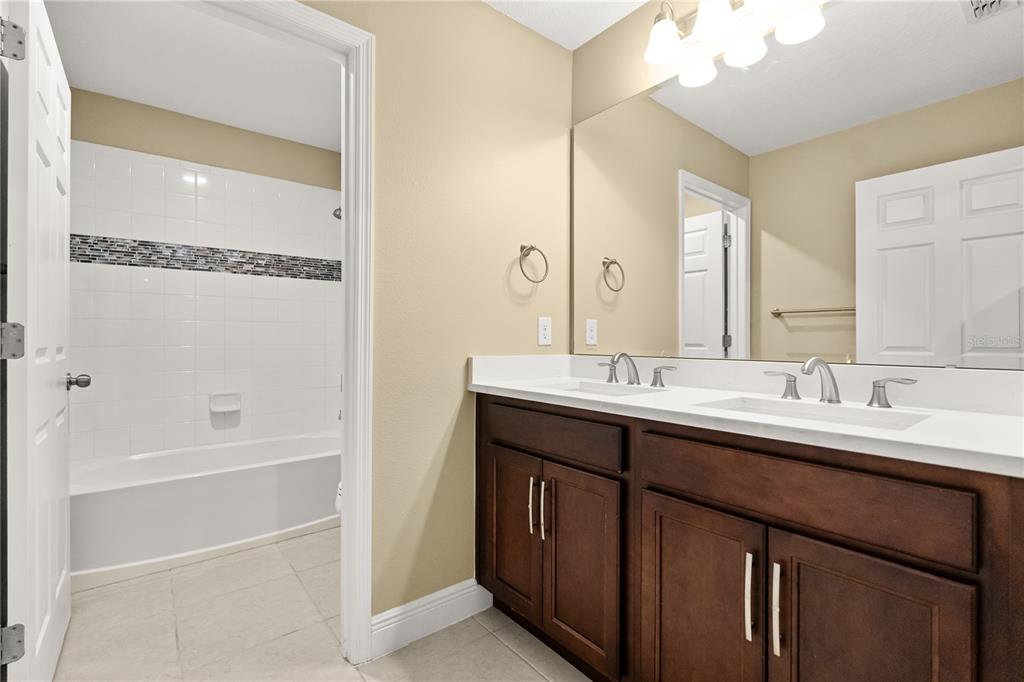 7757 Marsala Street Clermont, FL 34714 - Photo 37 of 75 a bathroom with a double vanity sink a mirror and a bathtub