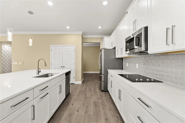 a view of kitchen with stainless steel appliances granite countertop a stove a sink a refrigerator and white cabinets with wooden floor