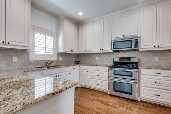 a kitchen with granite countertop white cabinets and stainless steel appliances
