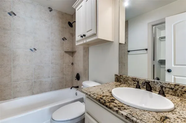 a bathroom with a granite countertop sink mirror toilet and bathtub