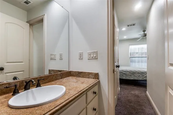 a en suite bathroom with a granite countertop sink and a mirror