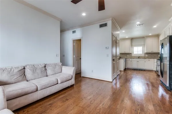 a living room with stainless steel appliances kitchen island hardwood floor and a view of kitchen