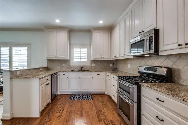 a kitchen with stainless steel appliances granite countertop wooden cabinets stove top oven and sink