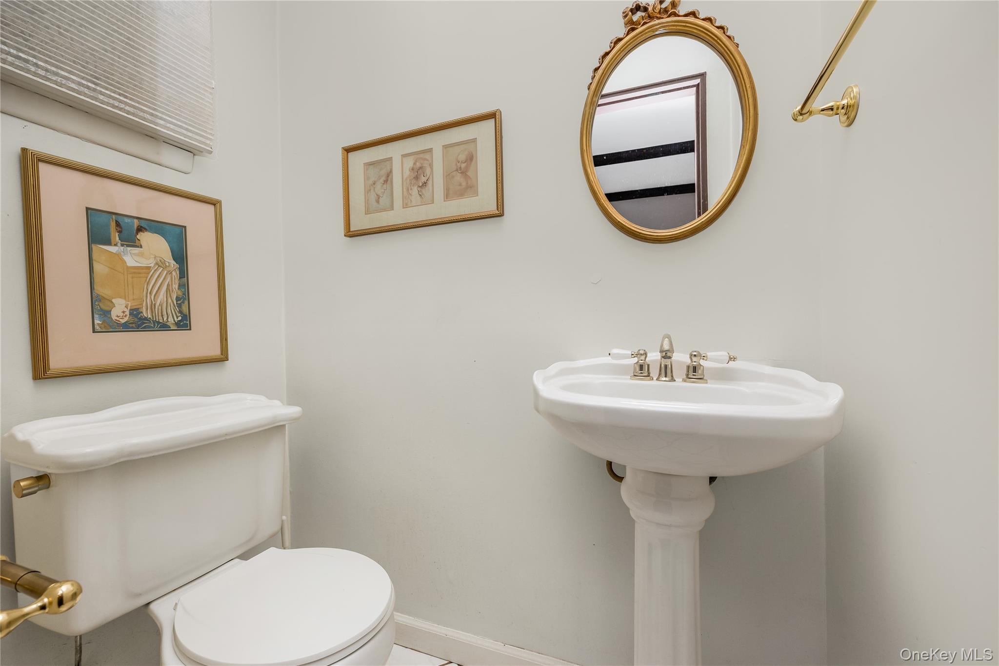 29 Randy Lane Plainview, NY 11803 - Photo 7 of 38 Half bath on main floor with pedestal sink, polished nickel faucet, white toilet with brass flush lever, and decorative oval mirror