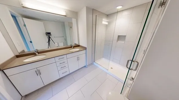 a spacious bathroom with a double vanity sink a mirror and a shower