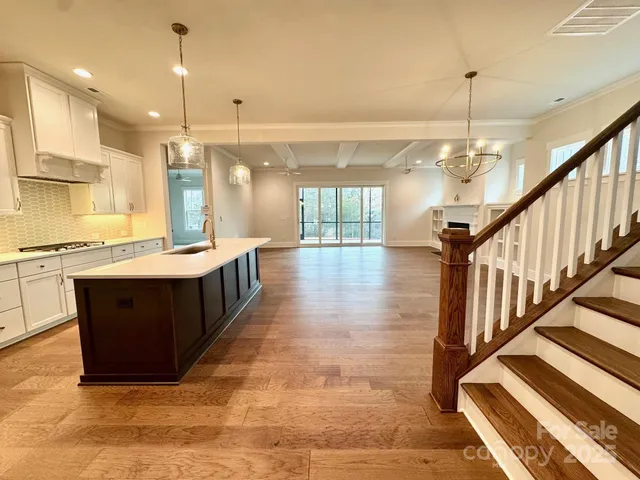a large white kitchen with lots of counter space a sink and a chandelier
