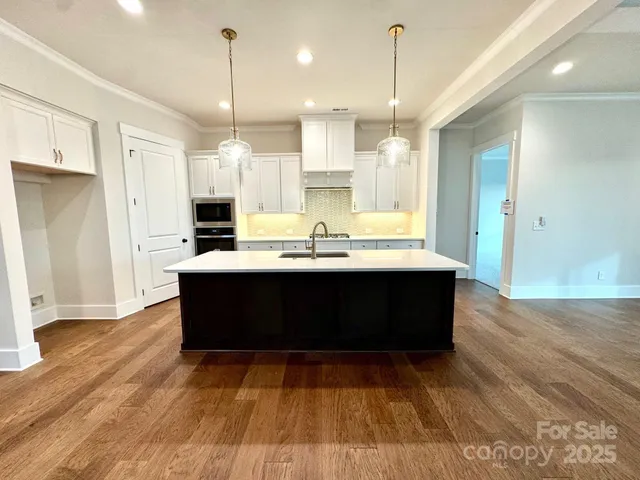 a room with kitchen island granite countertop wooden floors and wide view