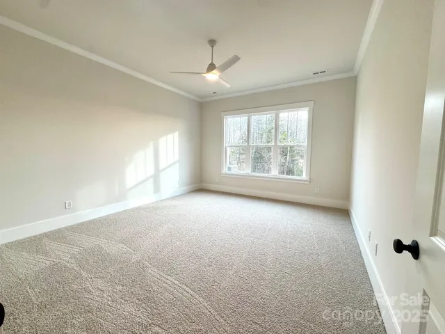 an empty room with windows and chandelier fan