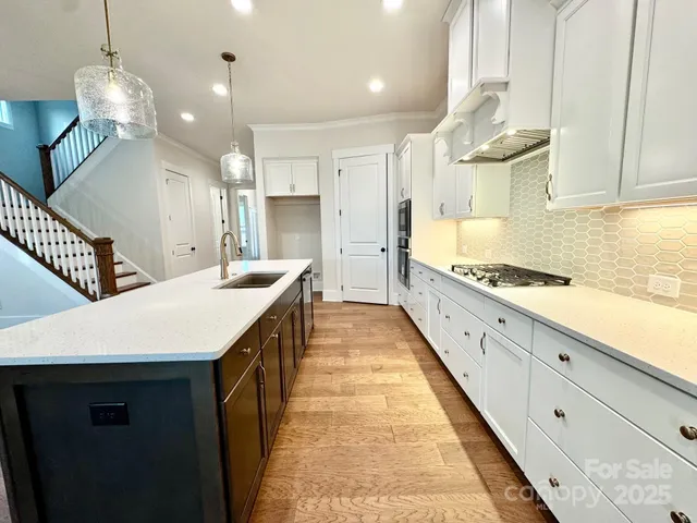 a large kitchen with cabinets a sink dishwasher a stove and a dining table with wooden floor