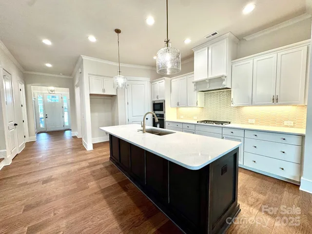 a kitchen with kitchen island granite countertop a sink appliances and cabinets