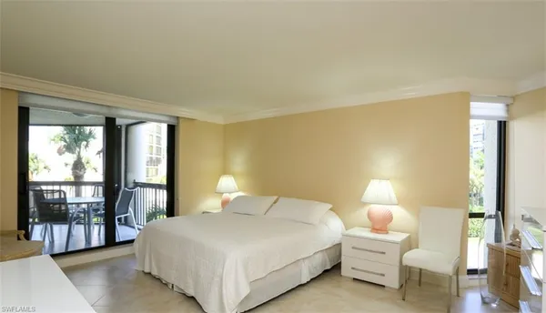 a bedroom with a bed lamp and a large window