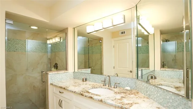 a bathroom with a granite countertop double vanity sink and a mirror