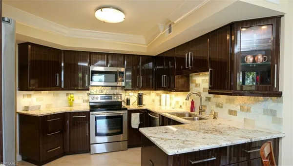 a kitchen with stainless steel appliances kitchen island granite countertop a stove refrigerator and cabinets