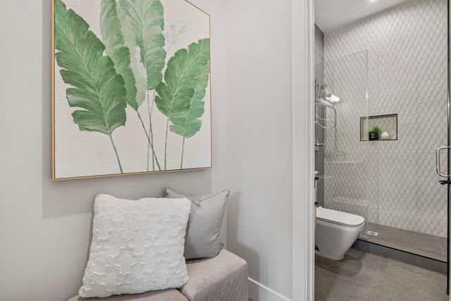 a bathroom with a toilet and a painting on the wall