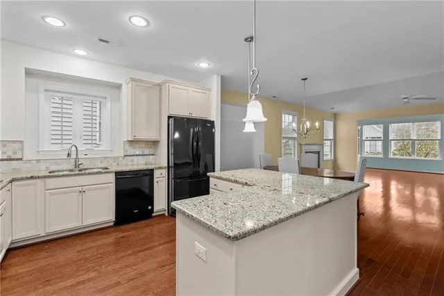 a kitchen with stainless steel appliances granite countertop a sink a stove a refrigerator and island with wooden floor