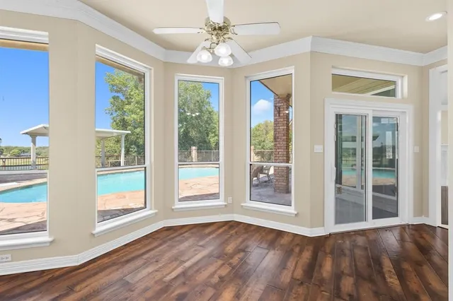 a view of an empty room with a window and wooden floor
