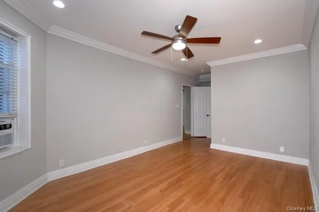 a view of an empty room with wooden floor and a ceiling fan