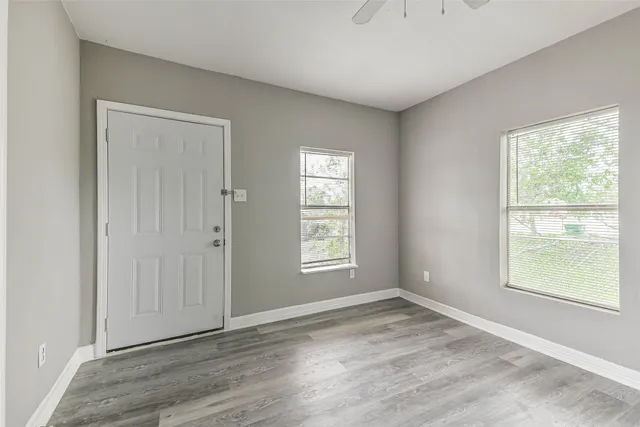 an empty room with wooden floor and windows